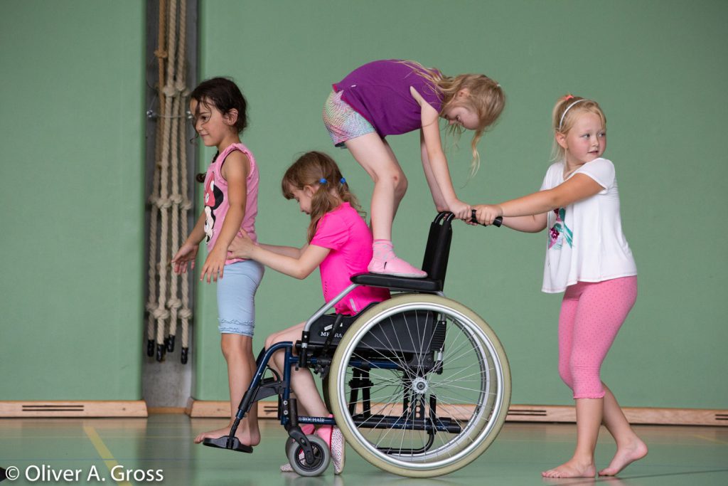 Vier VolksschülerInnen machen eine Rollstuhlskulpur.